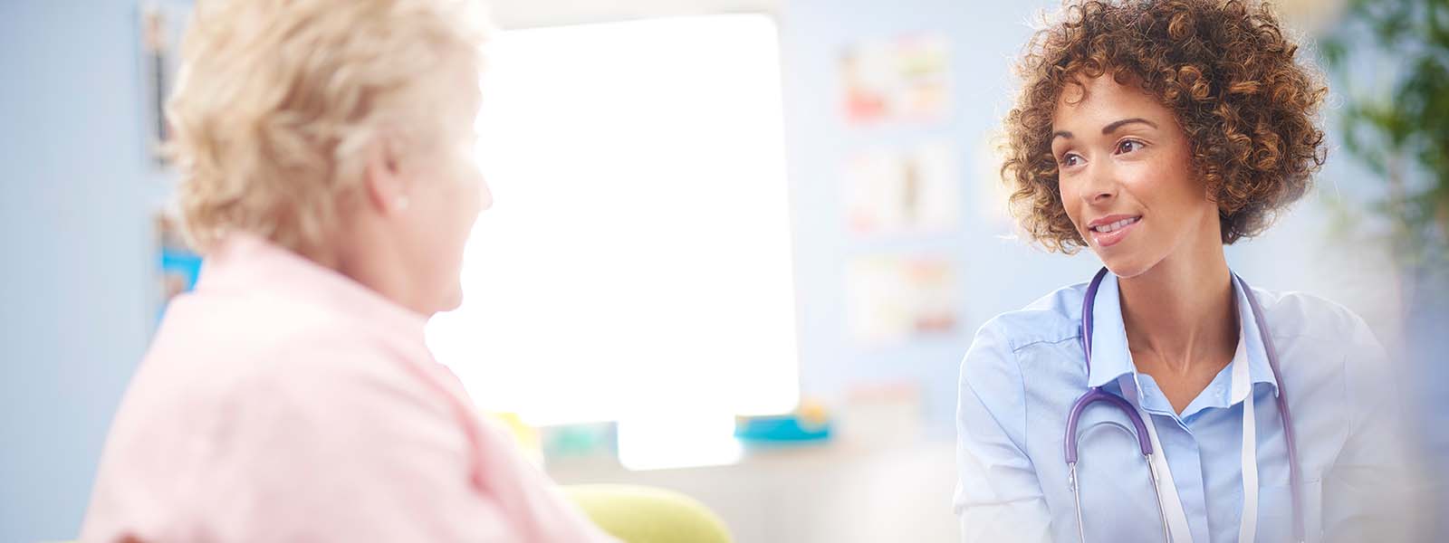 a female doctor sits and listens to a senior woman sitting down in a consultation room